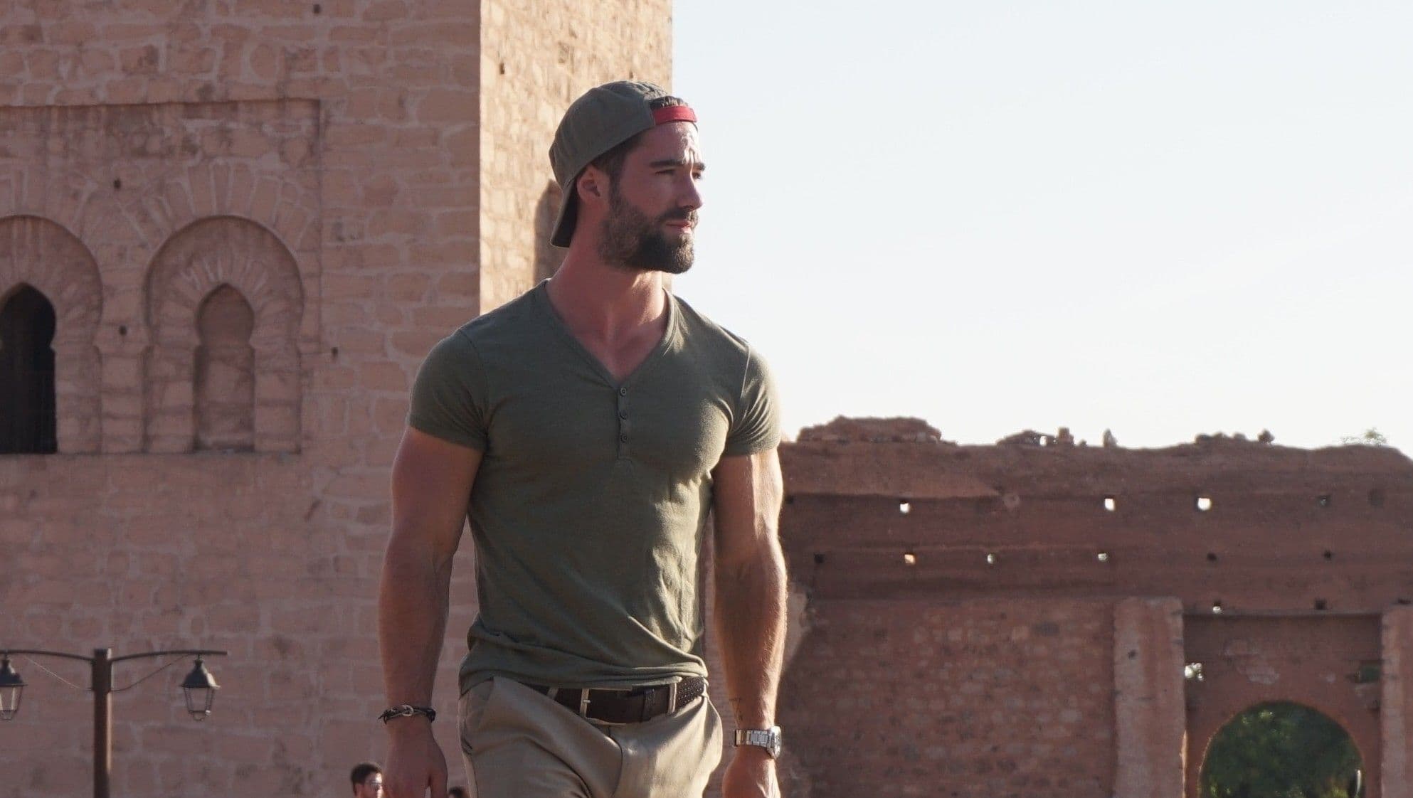 Nikjas Sakowski geht vor einer alten Lehmmauer in Marrakesch und schaut in die Ferne